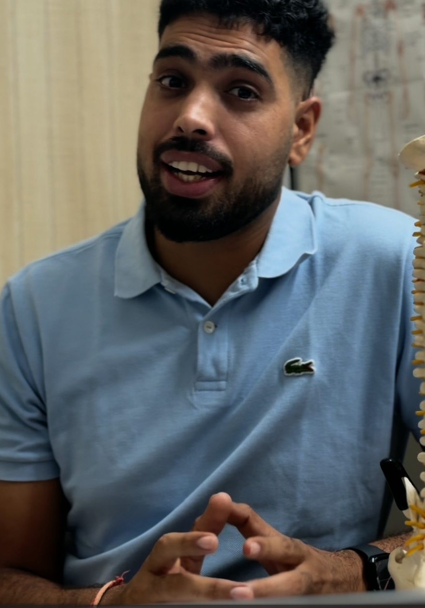 Dr. Akshay Sharma, founder of ART Physiotherapy Clinic, explaining spinal anatomy with a spine model