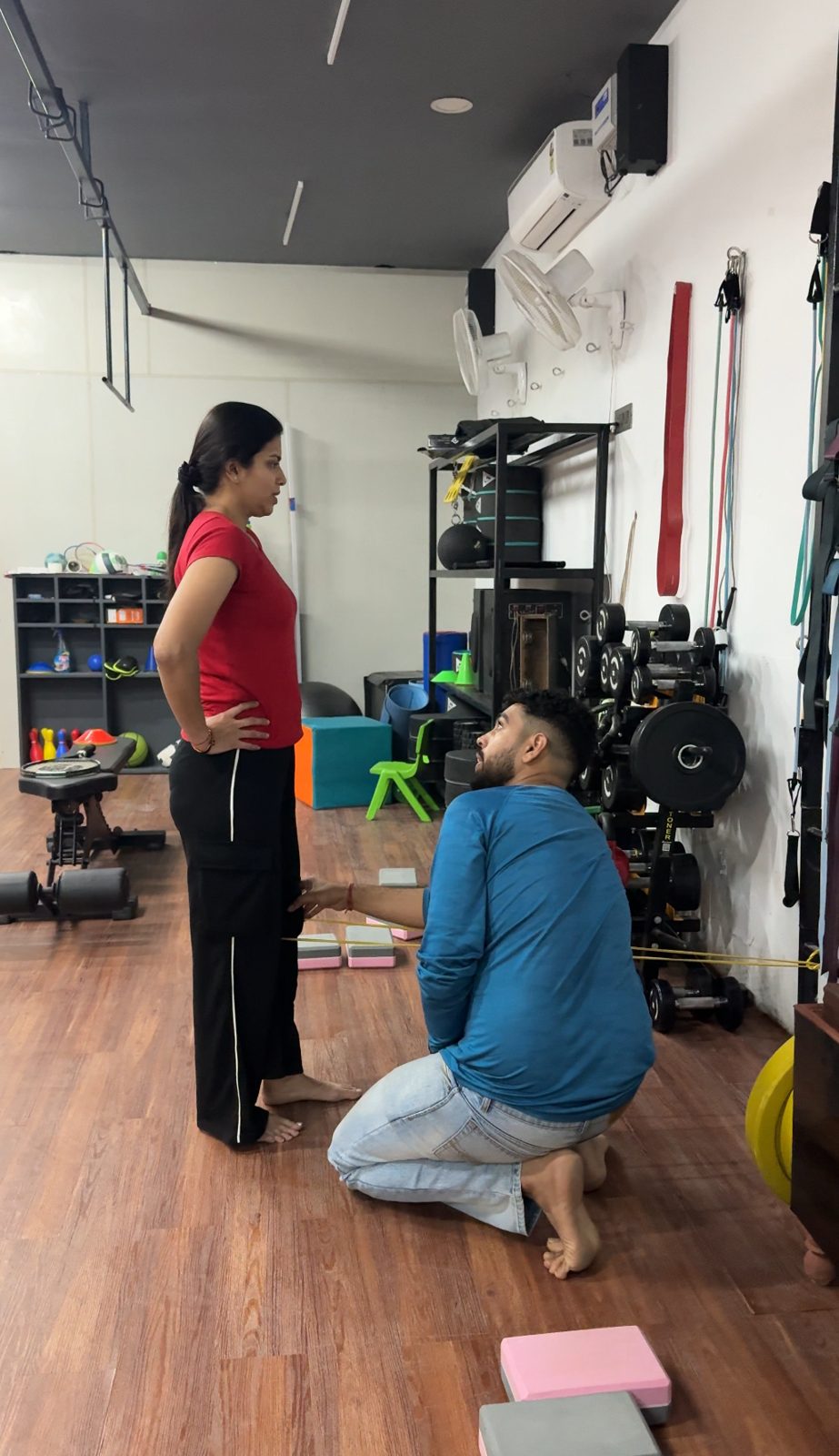 Coach guiding a patient through resistance-band work in the strength room