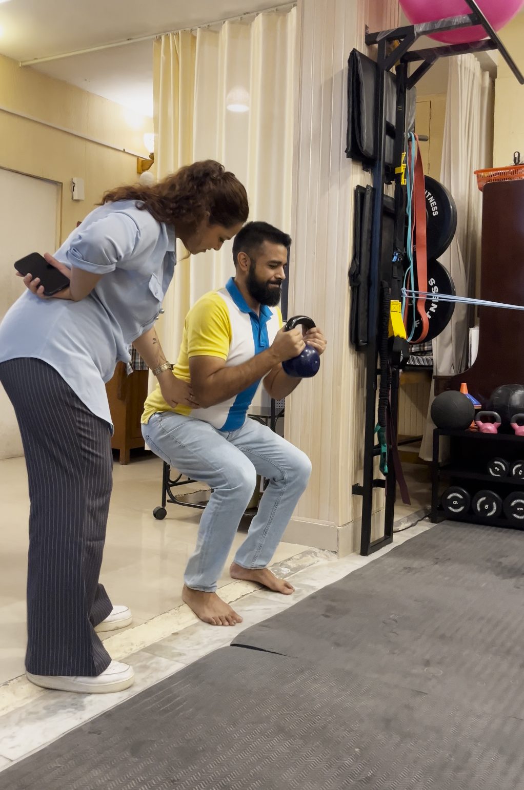 Coach guiding a patient's form during a kettlebell goblet squat